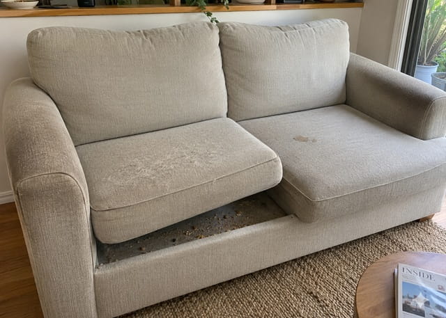 Worn fabric sofa with stains, darkened armrests and flattened cushions – signs it needs professional cleaning